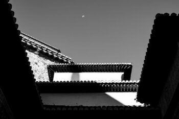 Photo en noir et blanc d’un bâtiment asiatique avec une lune dans le ciel.