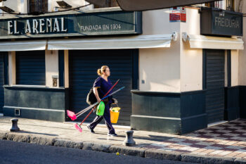 Une femme marchant dans la rue avec une serpillère et un balai en Andalousie.