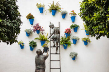 Une statue d'un garçon debout sur une échelle à côté de plantes en pot en Andalousie.
