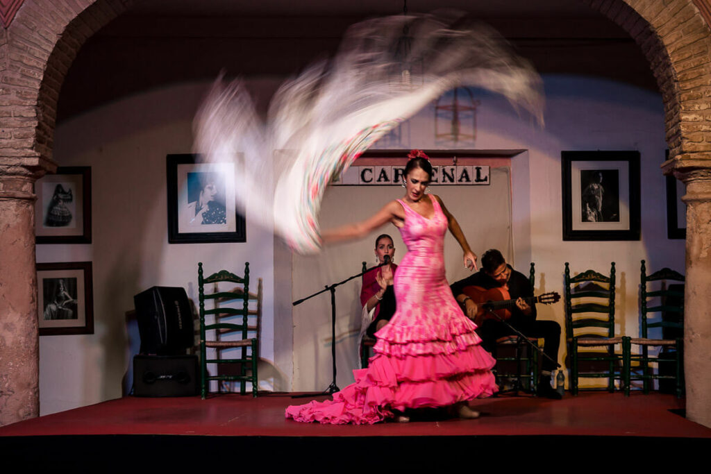 Une femme en robe rose danse devant une arche en Andalousie.