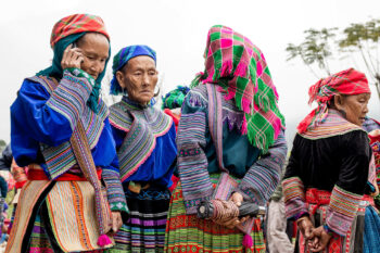 Un groupe de femmes vêtues de vêtements colorés parlent sur leur téléphone portable au Vietnam.