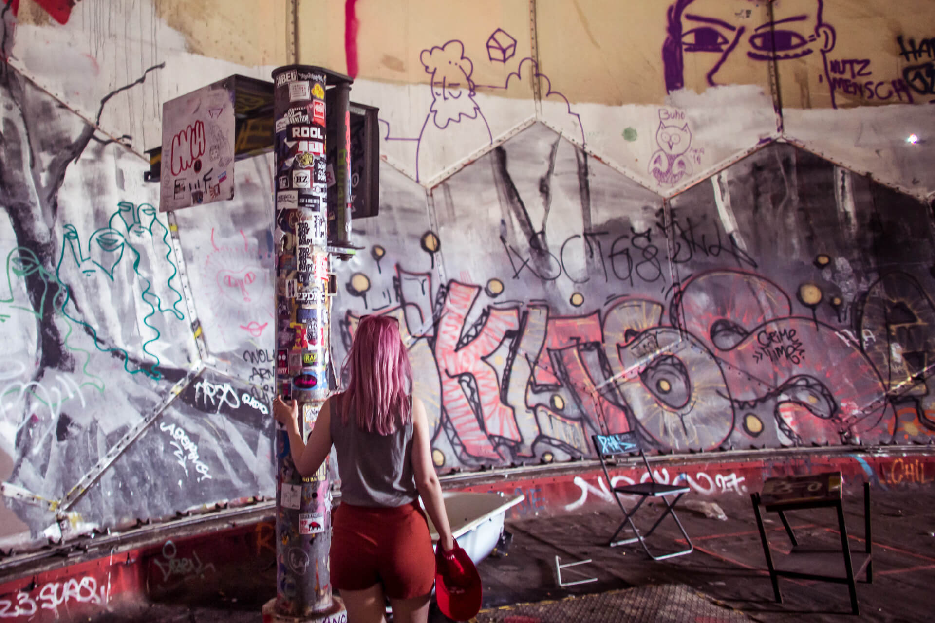 Une femme debout à côté d’un mur couvert de graffitis à Berlin.