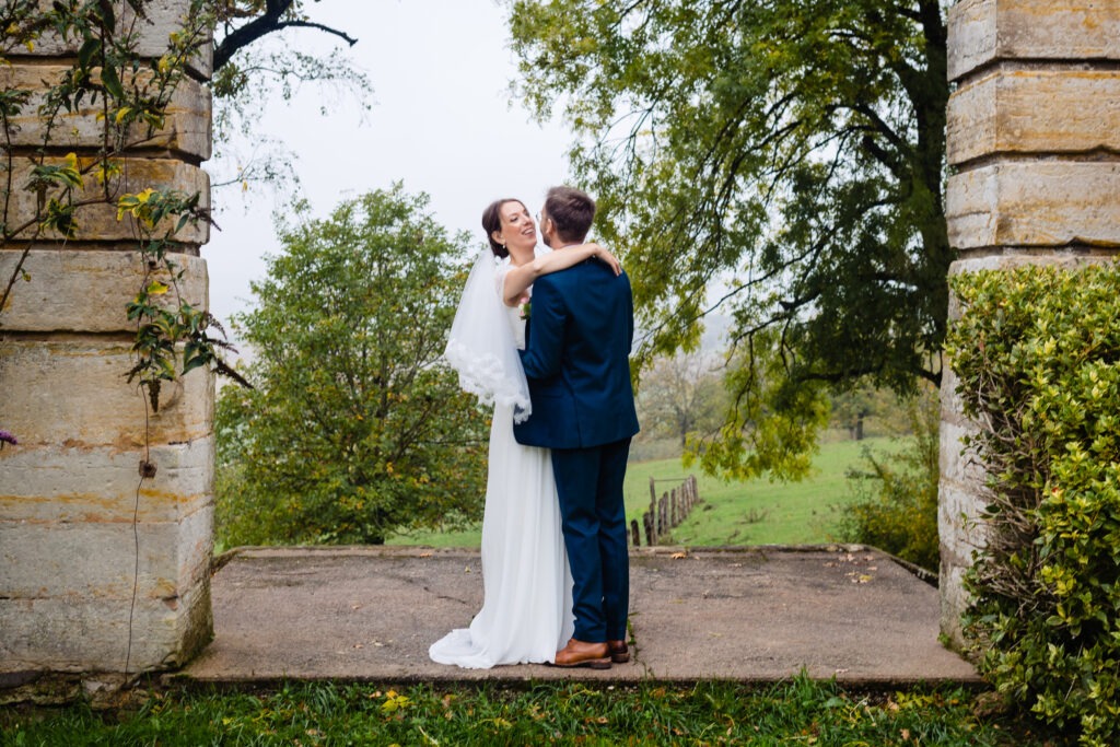Pauline et Vincent, mariés, s'embrassent lors de leur cérémonie de mariage devant une arcade, en prévision de leur Mariage 2022.