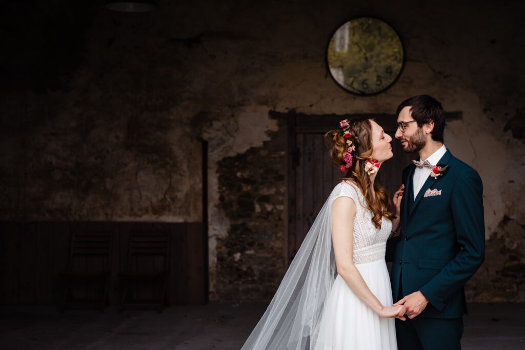 Laura et Thomas célèbrent leur mariage par un baiser romantique dans un immeuble ancien.