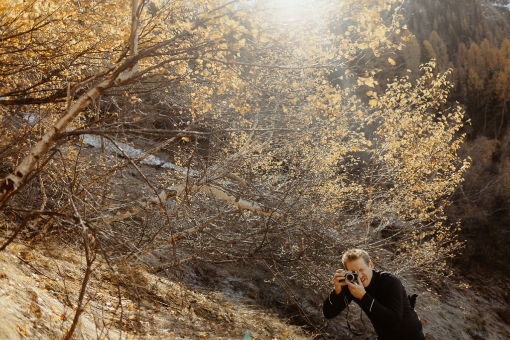 A woman takes a photo of a mountain tree.