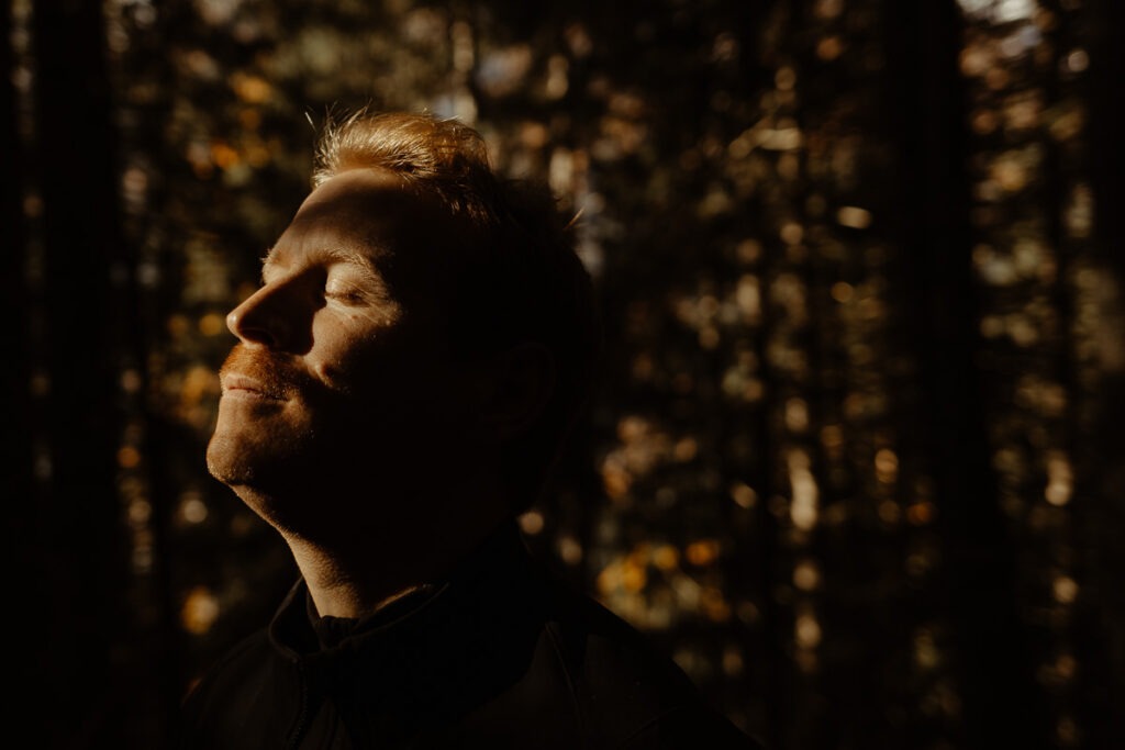 A man standing on Brorrick Mountain, eyes closed.