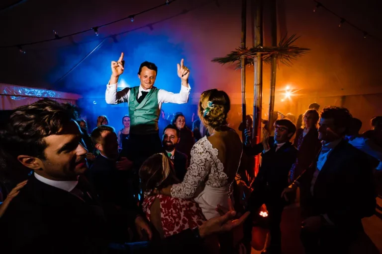 Jean-Baptiste porté en l'air par les invités, bras levés, sur la piste de danse du mariage
