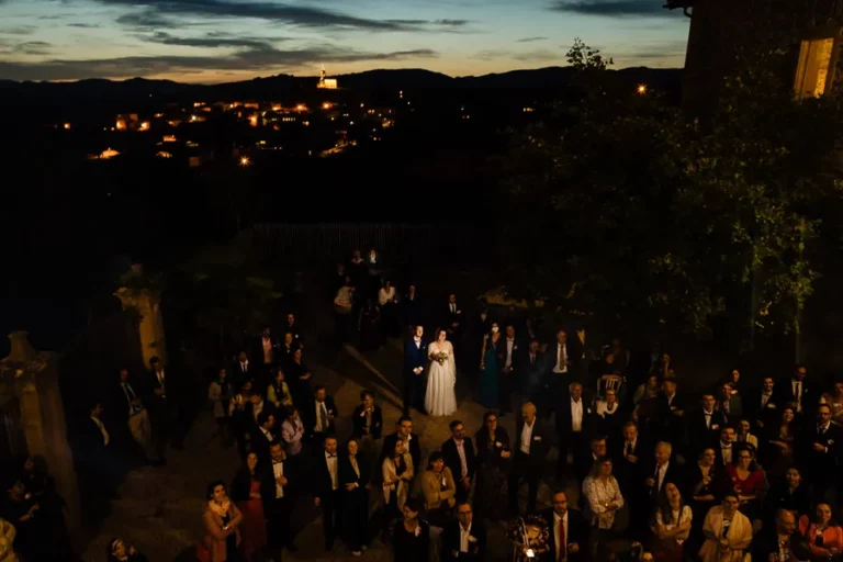 Mariage Bastide des Hirondelles Beaujolais : Mayeul et Lorianne entourés des invités au crépuscule pendant le vin d'honneur