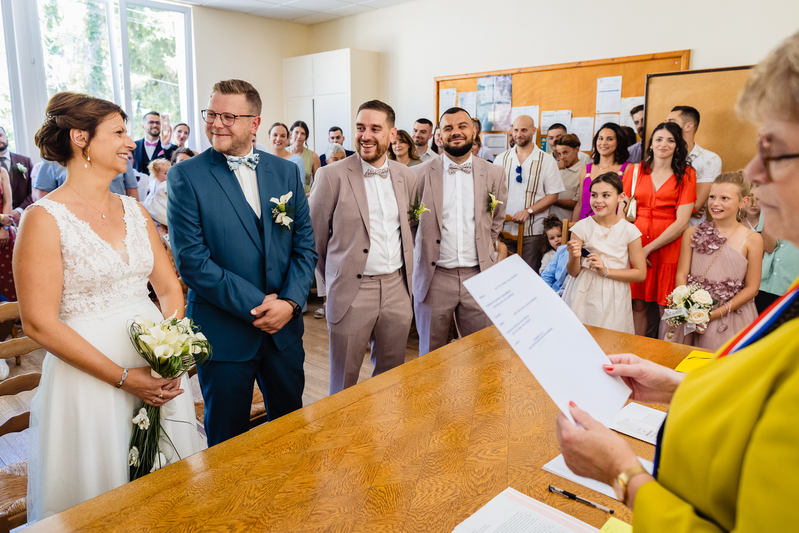 Kevin et Amélie entourés d'invités, officiel lit le document sur table en bois, mairie Orbigny