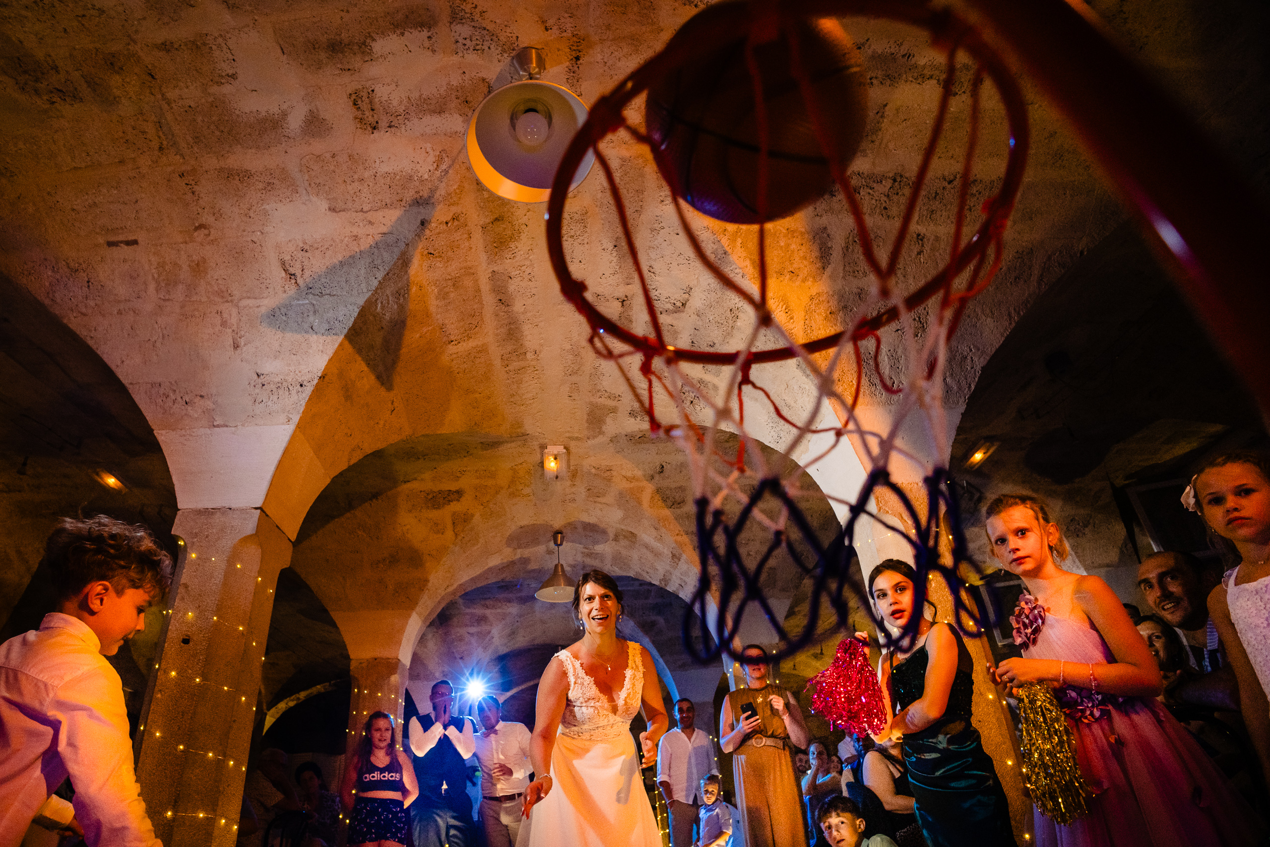 La mariée lance le ballon de basket, invités et enfants applaudissent sous les voûtes Ferme Sainte-Anne