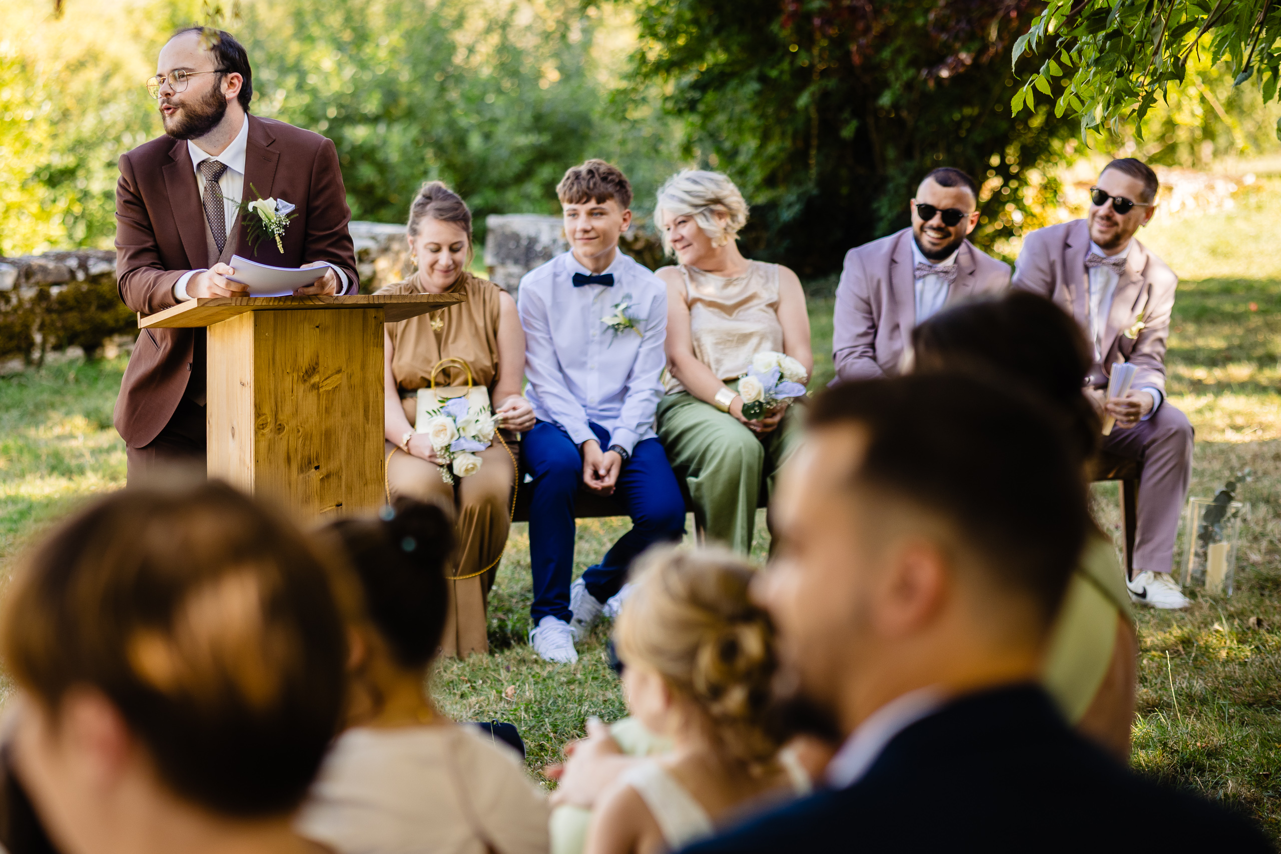 Le frère de Kevin au pupitre en bois, invités assis en tenue de soirée, cérémonie laïque Ferme Sainte-Anne